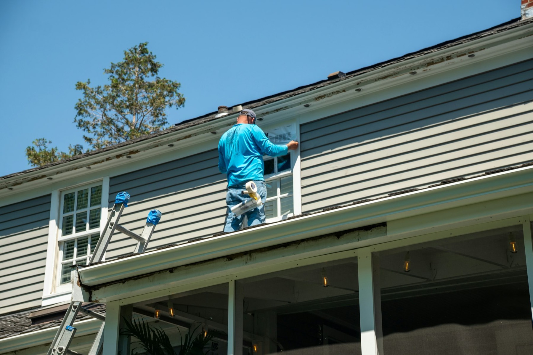 A person applying tape to a window on a house
